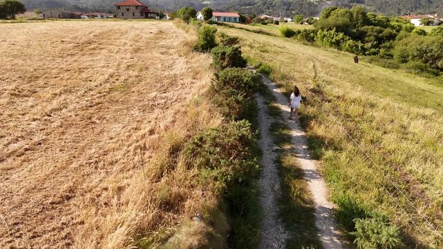 Aerial shot of a model released woman walking a narrow country lane between fields