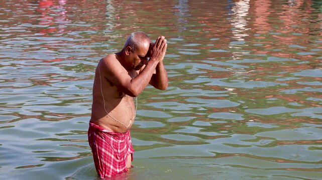 Hindu Devotee Offering Prayer While Standing in Sacred River During Holy Bath Ritual