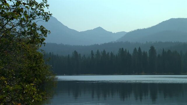 Misty mountain layers reflecting in a calm lake at Lassen Volcanic National Park, California