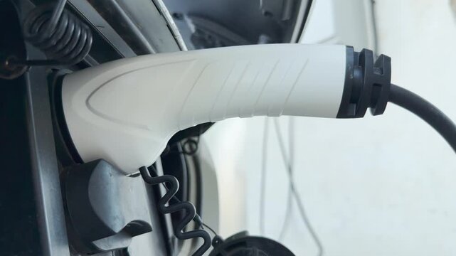 The electric vehicle charging plug connects to the port. This simple act powers the car efficiently. It feels like a hopeful, clean step toward a brighter, sustainable future.