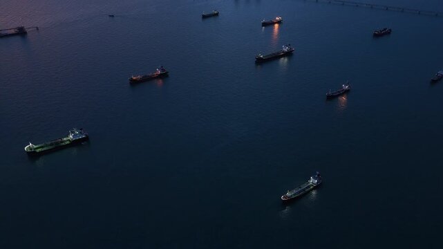  heavy oil tankers and LNG vessels anchored at a strategic maritime chokepoint during a golden sunset, emphasizing global energy crises and petroleum supply chain infrastructure.