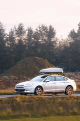 Naklejka premium Modern car with roof storage box on road trip