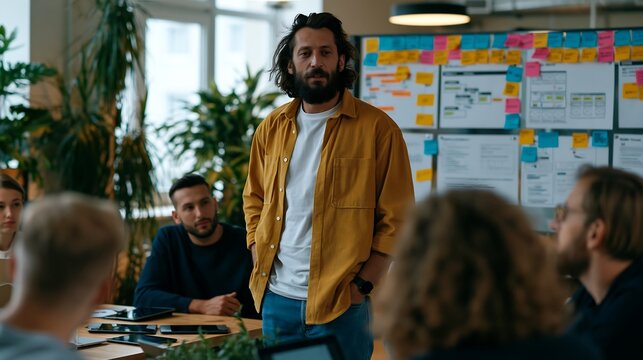 Young team leader standing and presenting to colleagues near an agile scrum board with sticky notes in a creative office.