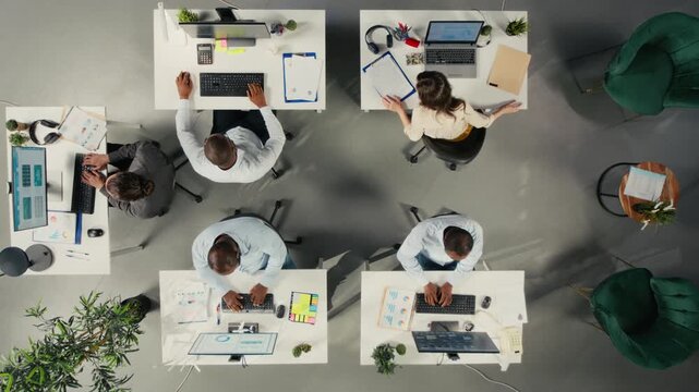 Business colleagues review forecasting data from an overhead angle inside a modern office, combining forecasting data while they connect analytics with management goals.
