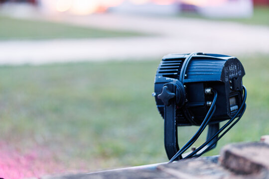 Professional LED stage light setup outdoors stage light projector installed on the ground, facing towards an outdoor event area during sunset with a beautiful blurred bokeh background and copy space.