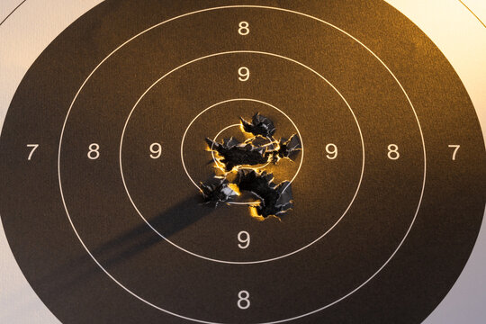 Close up of paper shooting target with multiple bullet holes in the bullseye center, concept for accuracy success perfection and achieving business goals