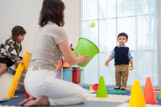 Children play with colorful toys in a bright room as a woman helps them learn and have fun together