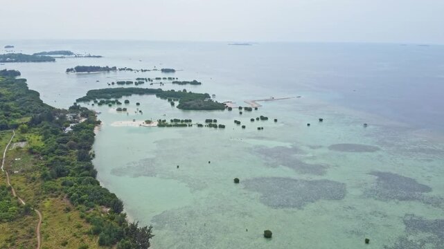 Aerial view of a tropical island archipelago featuring green mangrove forests, shallow coral reefs, and white sand beaches surrounded by a clear turquoise ocean. Pari Island, Indonesia