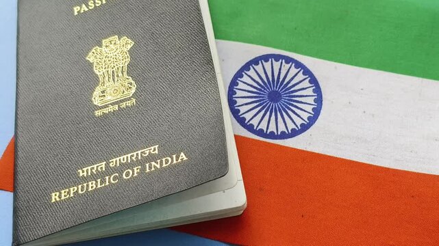 Passport of India isolated near Indian national flag. India citizenship or nationality identification document proof for international travel. Closeup rotating top view. Personal identity concept.