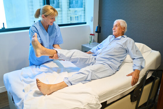 Healthcare professional assisting senior in physical therapy at rehabilitation facility