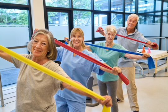 Seniors exercising with resistance bands under supervision in a rehabilitation facility