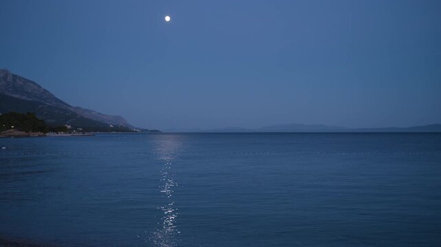 Moonlight reflecting on the calm Adriatic Sea in Brela, Croatia, featuring a peaceful blue hour seascape, tranquil water and a serene Mediterranean evening