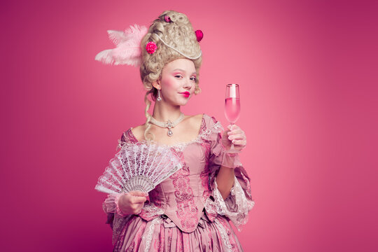 Photo of gorgeous pretty lady dressed pompous rococo costume enjoying champane wavig fan empty space isolated pink color background