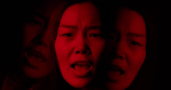 Woman scream in dramatic red lighting. Portrait of angry duality person, intense aggression, mental health disorder. Concept of fear, hysteria, instability, split mind. Two personality inner struggle