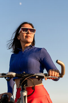 Woman bicycle summer outdoors exercising on a sunny day with clear blue sky backdrop for healthy lifestyle sports concept