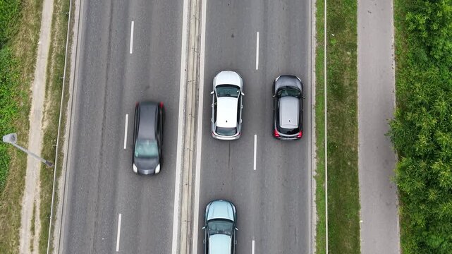 Aerial view of a traffic jam on a busy road, showcasing multiple vehicles including cars and a bus, surrounded by greenery and urban infrastructure in a vibrant setting