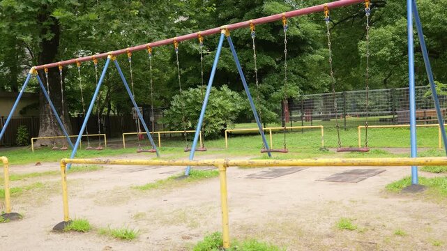 Empty swings swaying in an urban park playground
