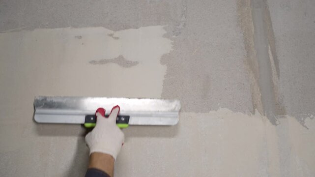Worker applying plaster to wall with trowel