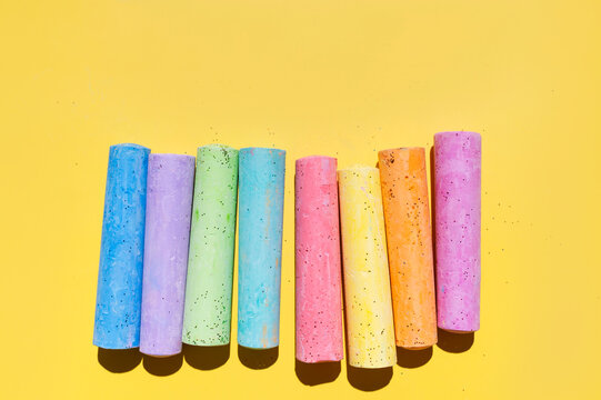 Colorful chalk sticks arranged on bright yellow background with wide copy space for creative layouts. Chalk supports education, classroom promotion, school branding and marketing materials 