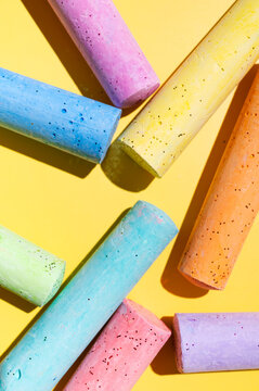 Macro shot of multicolored crayons for drawing and creativity. Crayons on a yellow background, top view. Materials for preschool and school education, children's drawing, and fun leisure activities.