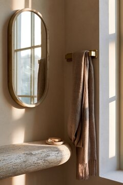 Brass wall hook with cashmere scarf beside round mirror in Scandinavian entryway