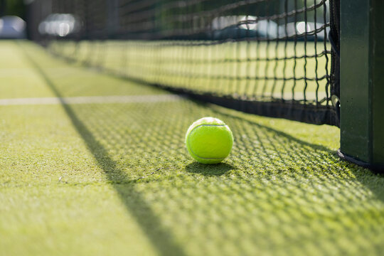 Bright greenish yellow tennis ball, court shadow and green texture of grass turf game match outdoor