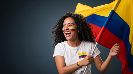 Fototapeta premium Excited curly woman holding Colombia national flag on pole, happy Colombian sports fan celebrating soccer football victory on grey background portrait