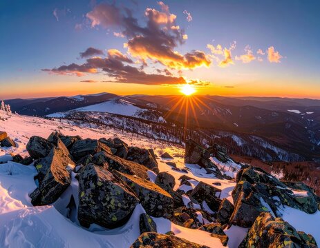 A stunning sunset over a snow-covered mountain range with dramatic clouds.