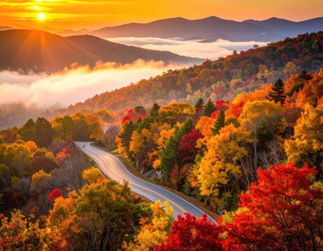 Scenic mountain road winding through vibrant autumn foliage at sunrise.