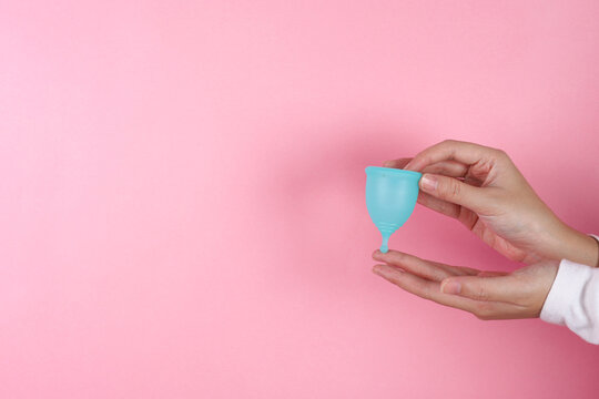 Two Hands Carefully Hold Silicone Menstrual Cup Against Solid Background