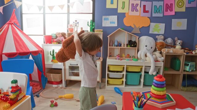 Boy holding a large stuffed bear over his shoulder in a colorful playroom with toys and storage bins; thoughtful comfort.