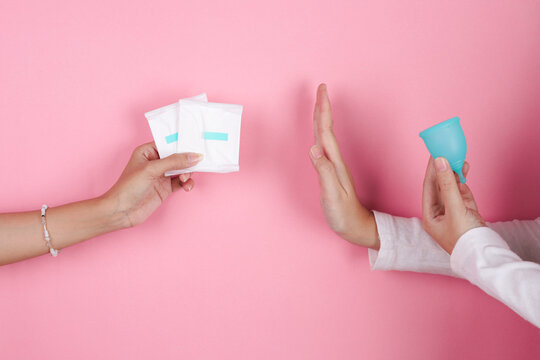 Hand Rejects Disposable Sanitary Pads With Stop Gesture While Another Holds Reusable Menstrual Cup