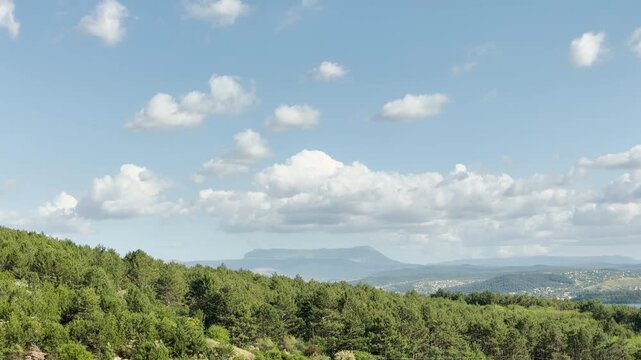 Mount Chatyr-Dag stands quietly on the distant horizon over a lush green forest in Simferopol, Crimea. This vast, sunny view under the blue sky brings a joyful and deeply peaceful feeling.