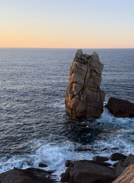 Distinctive sea stack with an unusual shape standing in the Atlantic Ocean off the Costa Quebrada coastline in warm sunset light. Cantabria, Spain.