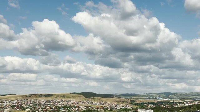 Cozy suburban houses spread across the rolling hills of Crimea. A vast sky filled with fluffy clouds creates a joyful and deeply peaceful feeling.