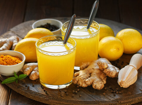 Immune booster antivirus drink, turmeric with ginger, lemon, mint and spices hot winter tea on wooden rustic background, closeup, natural medicine and naturopathy concept