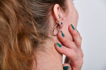 Fototapeta premium Nahaufnahme eines gepiercten Ohrs mit modernem Ohrschmuck. Stilvolles Beauty- und Fashion-Motiv zu Piercings, Schmuck, Individualität, Körperkunst und Lifestyle.