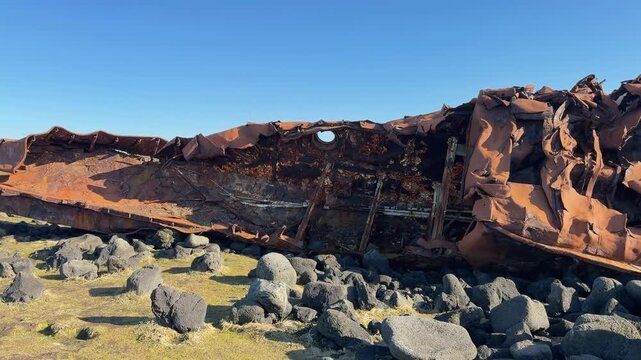 An upclose look at a crushed shipwreck in Grindavik, Iceland, stuck amongst a rocky shoreline on a bluebird day in Iceland
