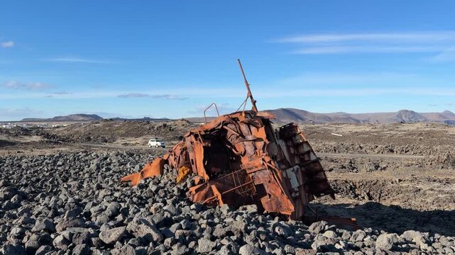 An old rusty shipwreck buried in the stone-filled beach near Grindavik, Iceland, shines in the sun on a gorgeous bluebird day in the land of fire and ice