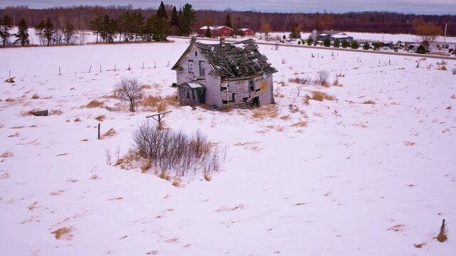 Aerial pan over a quiet winter landscape showcasing a deteriorating old barn.