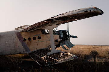 Corroded vintage biplane wings damaged by time, illuminated by sunset light, creating a steampunk-inspired industrial atmosphere. © Yaroslav