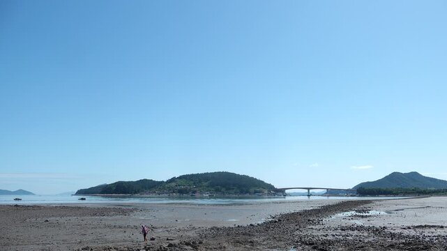 Scenic view of a peaceful Korean southern sea fishing village with local fisherman boats, mudflats, and islands in Namhae / 한국 남해바다 어촌 마을 풍경, 어민들의 고기잡이 배와 평화로운 섬, 갯벌 해안가 풍경 영상