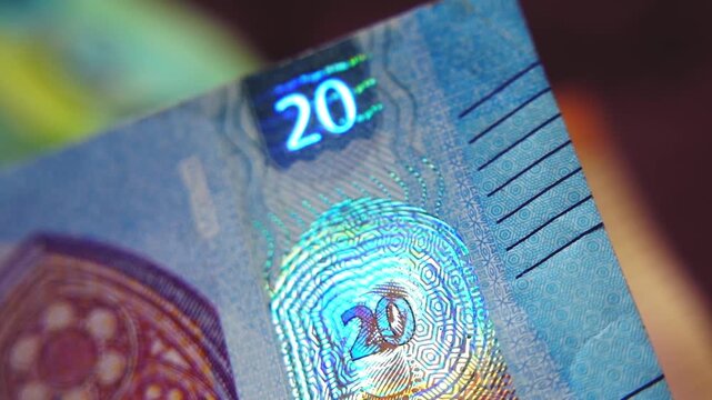 A close-up of the security strip with holographic emblems on the 20-euro banknote. Glowing security holograms on the 20-euro banknote. 4K macro slow motion video at 60 fps.