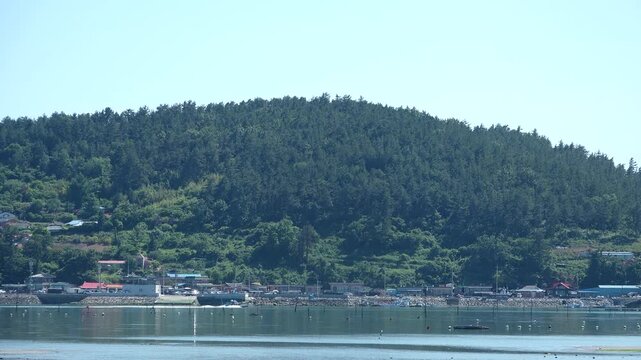 Scenic view of a peaceful Korean southern sea fishing village with local fisherman boats, mudflats, and islands in Namhae / 한국 남해바다 어촌 마을 풍경, 어민들의 고기잡이 배와 평화로운 섬, 갯벌 해안가 풍경 영상