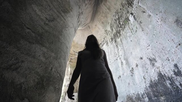 Young Woman walks in the Ancient Cave in Syracuse, Sicily, Italy. Ear of Dionysius, giant Cave with exceptional Acoustic