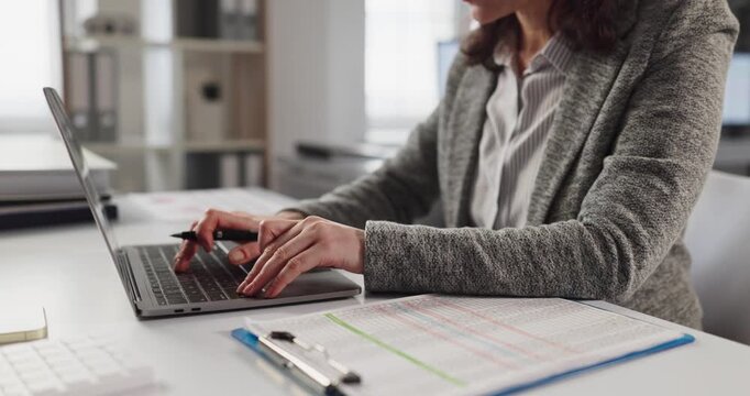 Woman accountant analyst in office typing laptop. She enters finance data from paperwork and audit sheets, ensuring accuracy and timely reports at a clean desk. Clear focus on financial accuracy.