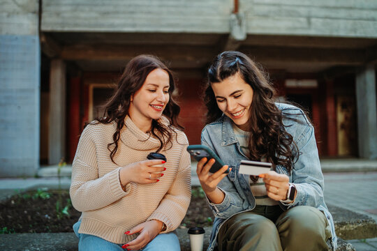 Two young women online shopping with credit card and smartphone