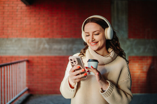 Young woman enjoying music and coffee in urban setting