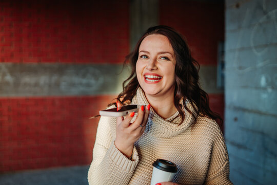 Woman recording voice message holding coffee cup