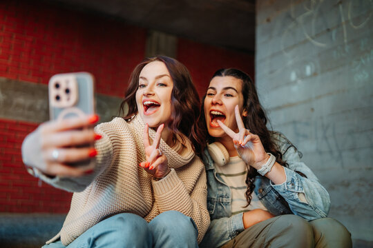 Young women friends making selfie with peace sign